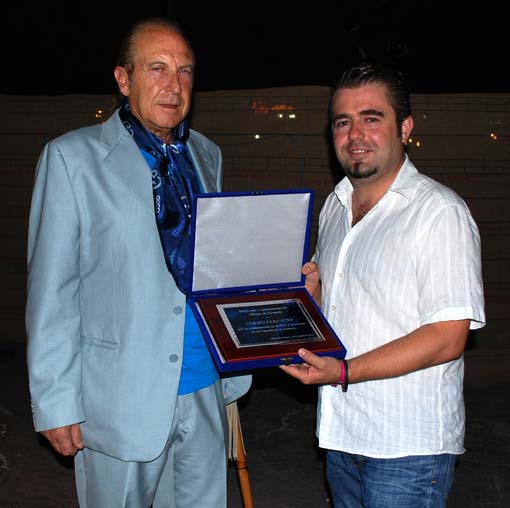 El concejal del Festival, muestra la placa de agradecimiento que se le entregó a Curro por su participación en la noche del 45º Festival 
